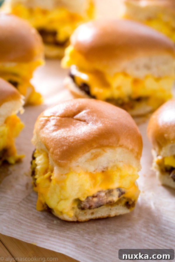 Overhead shot of freshly baked Sausage, Egg, and Cheese Breakfast Sliders with melted cheese oozing out, sliced and ready for serving.