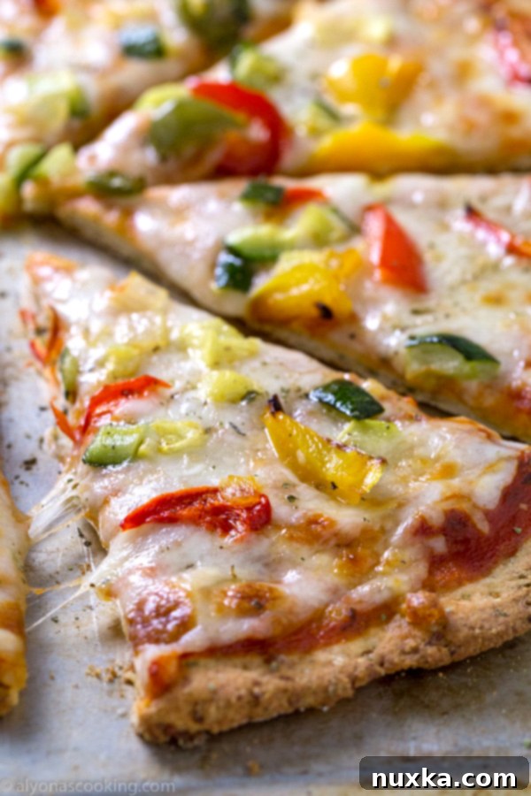 Cauliflower pizza crust topped generously with a colorful array of roasted vegetables, ready to be baked