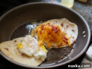 Topping toasted tortillas with shredded cheese, bacon bits, and a fried egg for quesadilla assembly.
