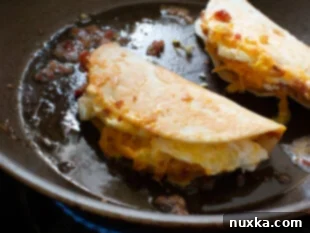 Folding a breakfast quesadilla in half and toasting it until the cheese melts and the tortilla is golden brown.