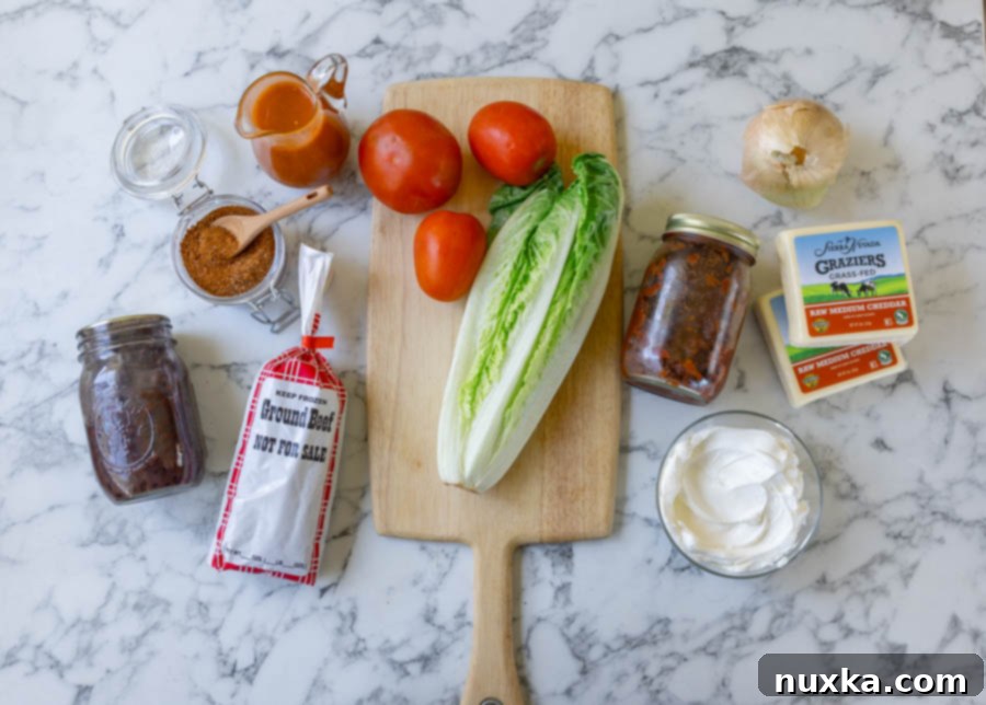 Taco salad ingredients (canned black beans, ground beef, taco seasoning, Catalina Dressing, tomatoes, onion, Romaine lettuce, salsa, sour cream, and cheddar cheese. 