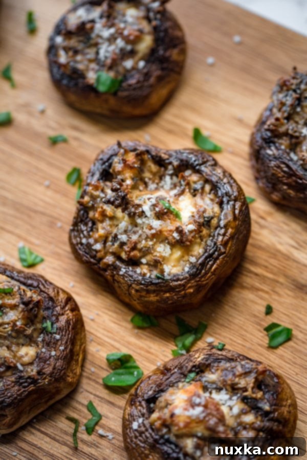 stuffed white button mushrooms with cream cheese and parmesan cheese on a cutting board