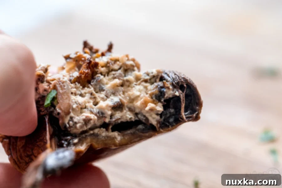 a bitten piece of cream cheese stuffed mushrooms 