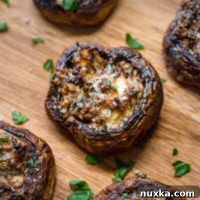 stuffed white button mushrooms with cream cheese and parmesan cheese on a cutting board