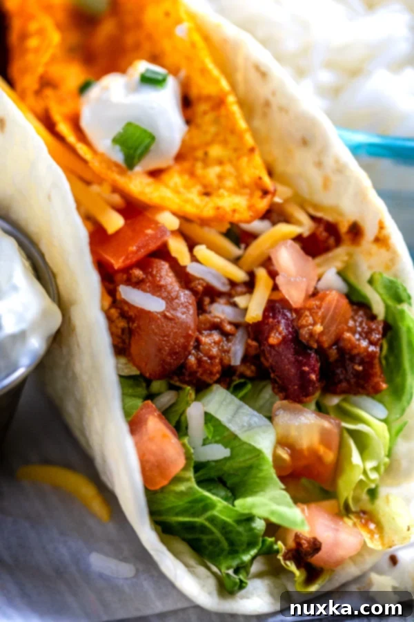 Delicious Soft Shell Tacos with hearty beef and beans filling, topped with cheese and fresh vegetables
