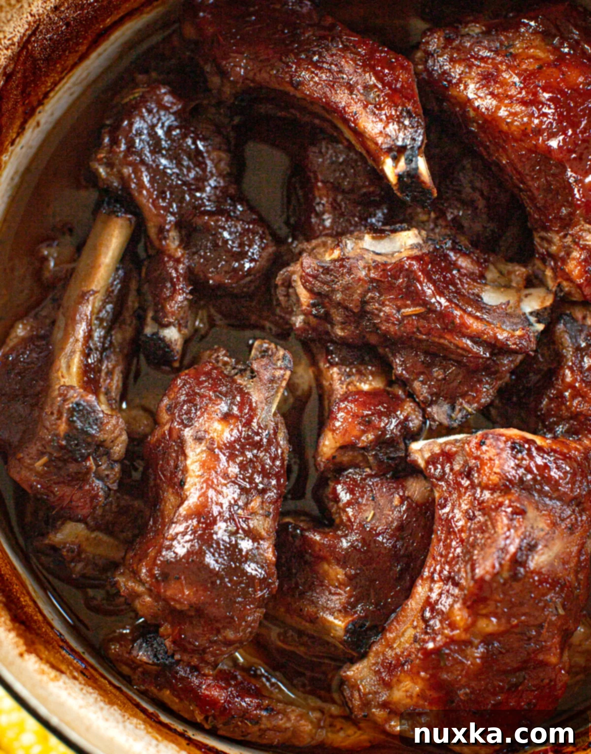 Perfectly braised short ribs from pork, glistening with BBQ sauce in a heavy dutch oven, ready to be served