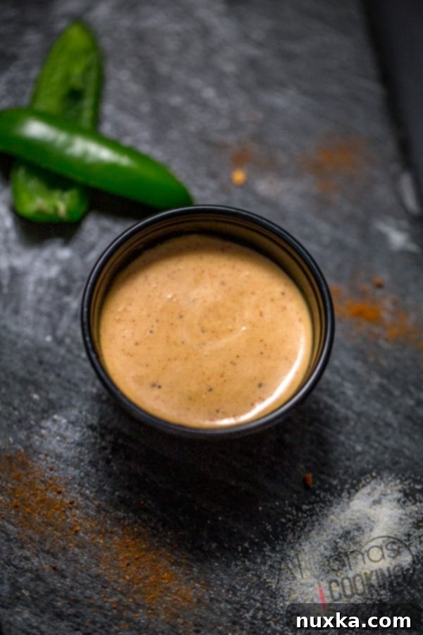 Homemade creamy jalapeño sauce, known as Taco Bell Quesadilla Sauce, in a clear glass container.