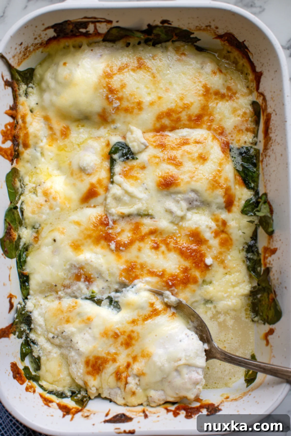 Delicious Creamy Spinach Chicken Casserole baking in a dish, showing melted cheese and tender chicken