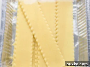 Lasagna noodle sheets soaking in hot water, ready to be used in the recipe.