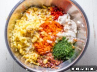 Potatoes, eggs, and carrots boiling in a pot for bacon potato salad.