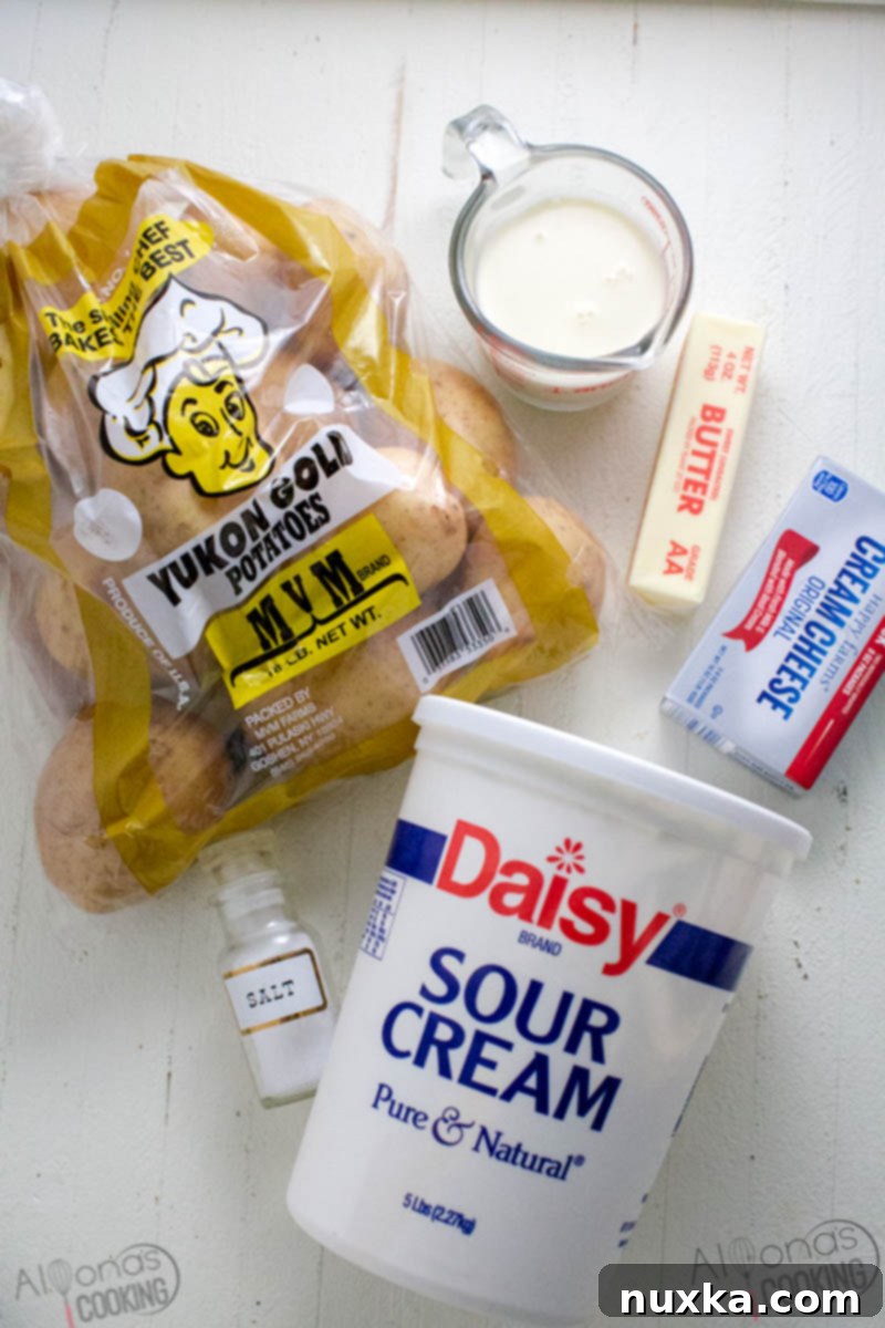 Ingredients for the best mashed potatoes, including Yukon Gold potatoes, cream cheese, sour cream, butter, salt, and milk for a rich and creamy side dish.
