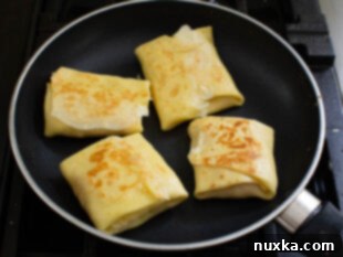 Toasting folded savory crepes until golden brown.