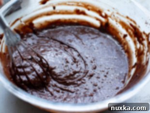 Adding wet ingredients to homemade brownie batter.