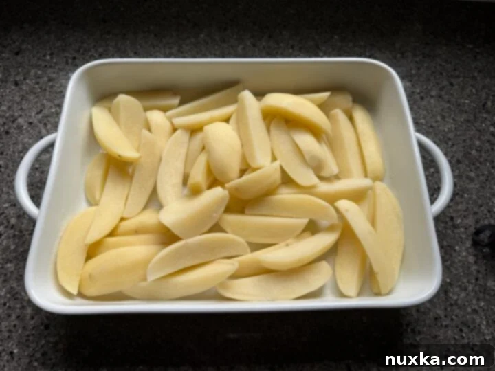 Cream-Infused Baked Potato Wedges 11 image of parboiled potatoes in a baking dish, perfectly prepared for the creamy sauce