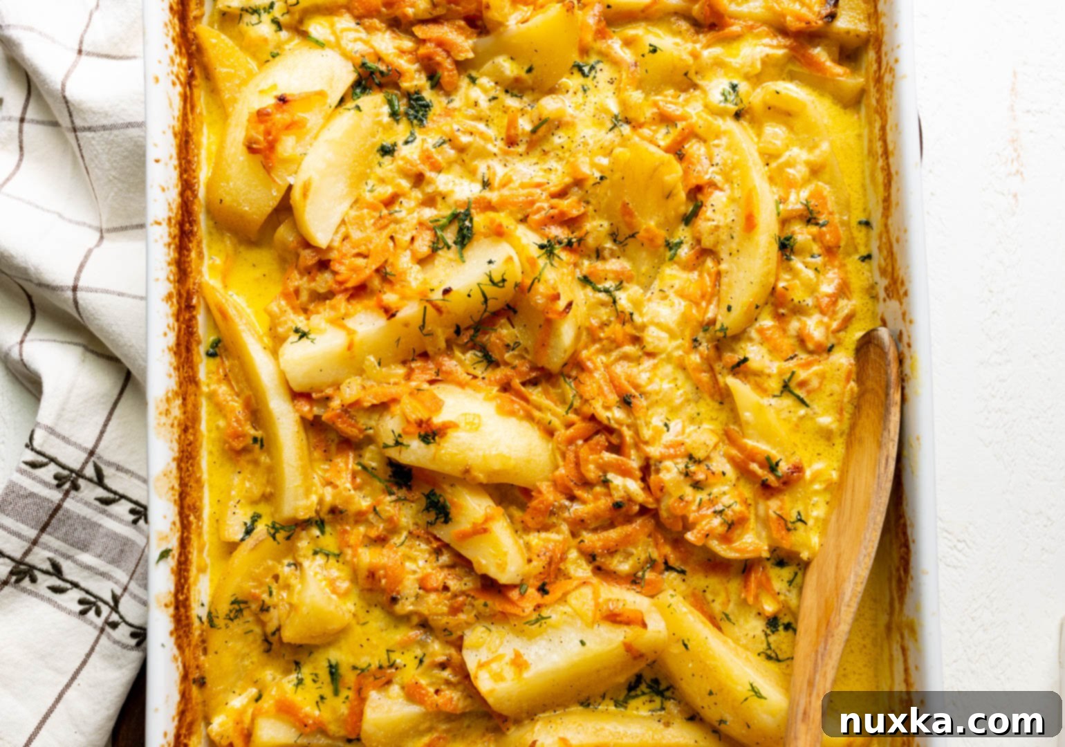 Cream-Infused Baked Potato Wedges 3 baked potato wedges in heavy cream sauce with carrots and onions garnished with fresh dill in a casserole dish