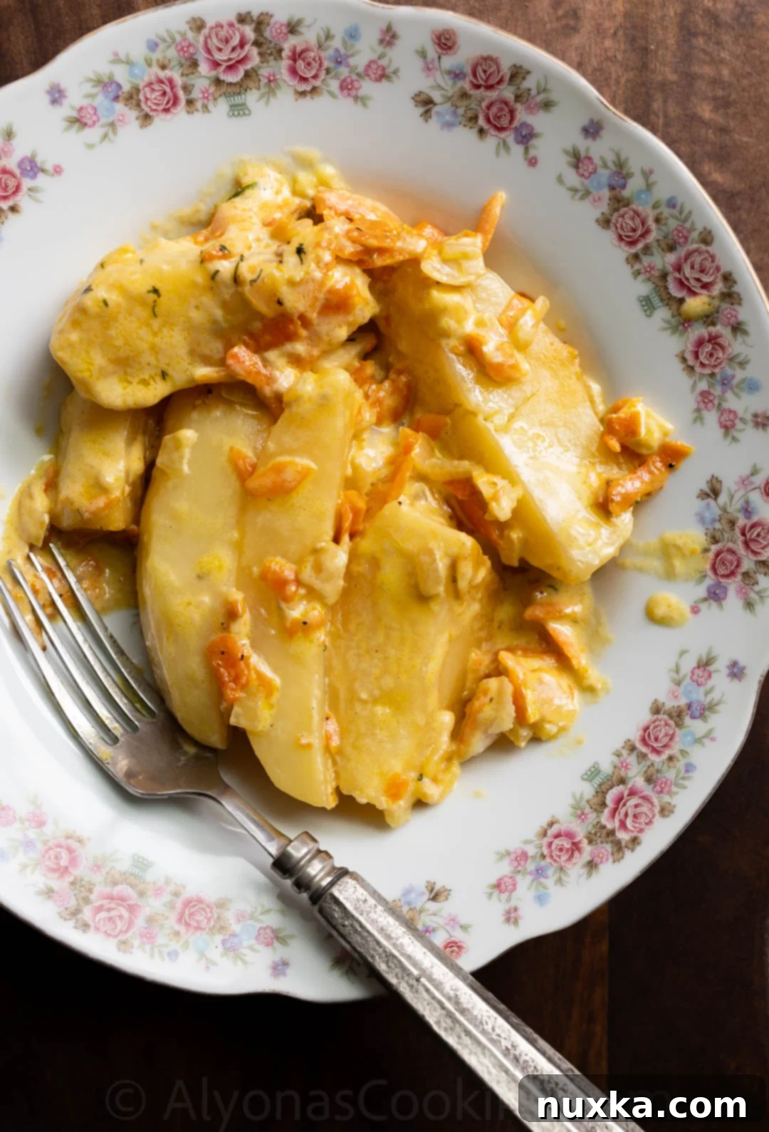 Cream-Infused Baked Potato Wedges 7 image of creamy potato wedges smothered in a heavy cream sauce with onions and carrots, garnished with fresh dill