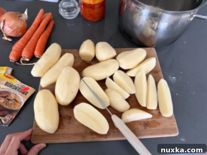Cream-Infused Baked Potato Wedges 9 image of russet potatoes being cut into uniform wedges for baking in heavy cream
