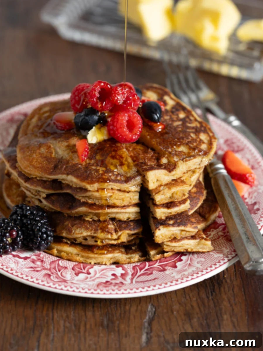 image of whole grain einkorn pancakes on a red vintage plate with berries and maple syrup