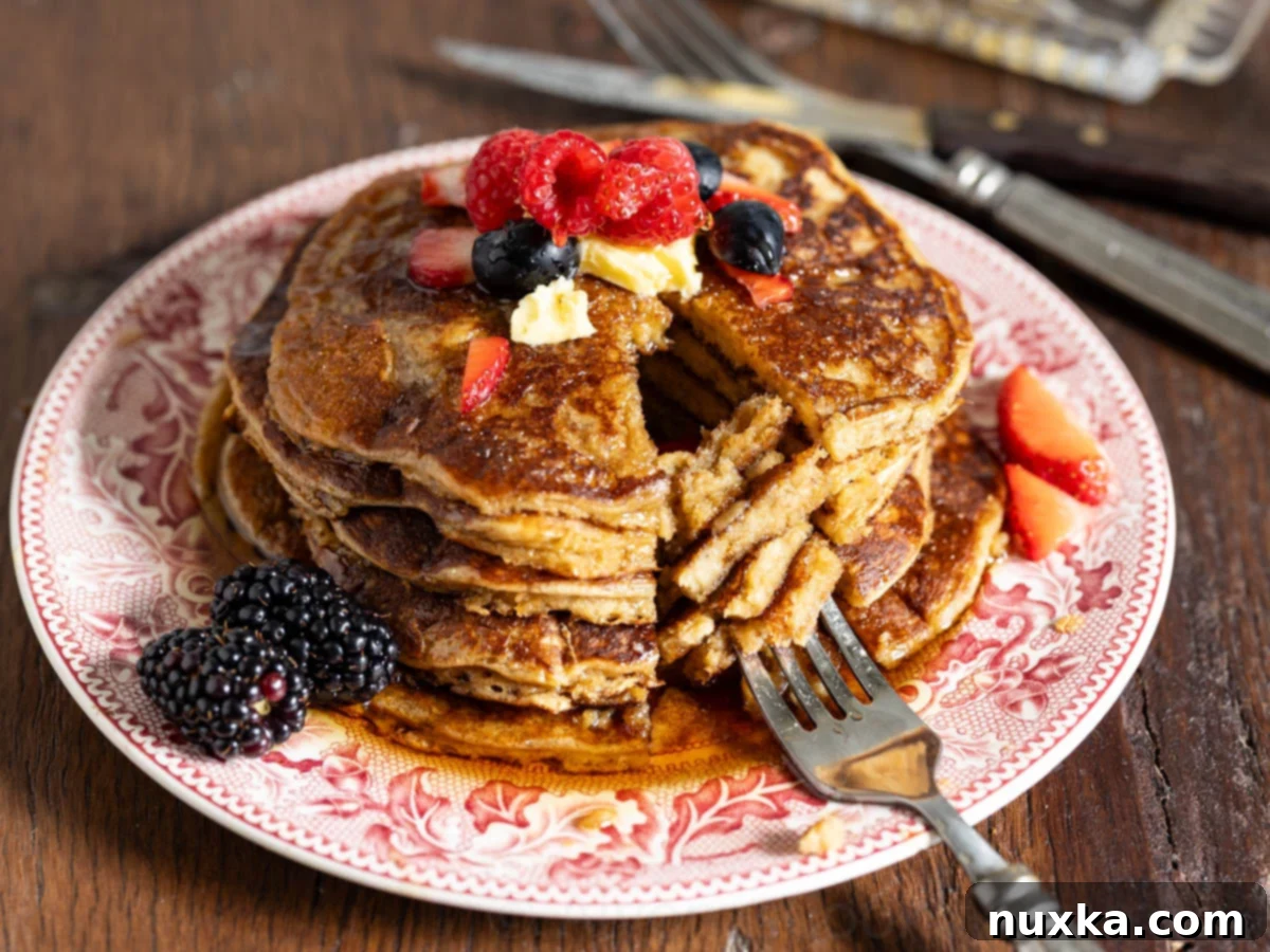 image of einkorn pancakes on a vintage red plate with a fork and berries 