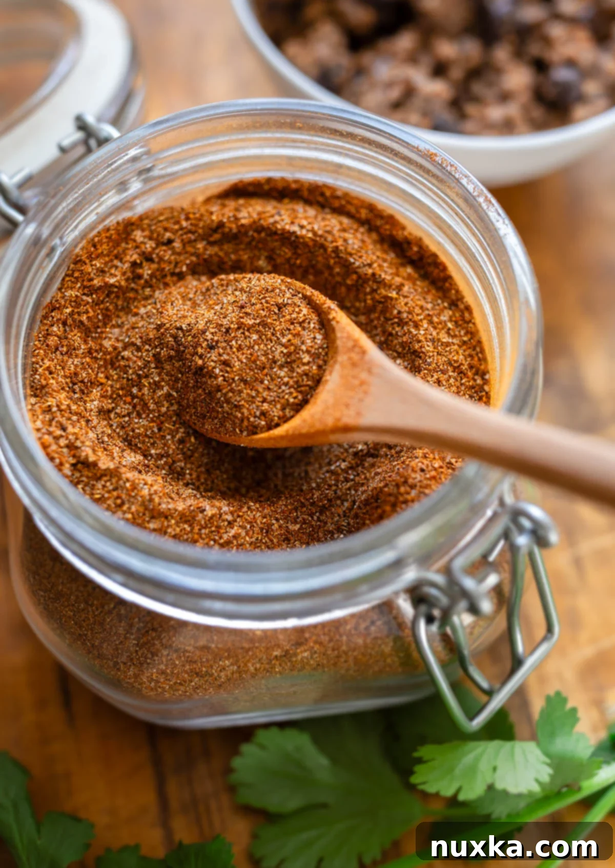A jar filled with homemade taco seasoning mix, ready for use in a well-organized pantry.