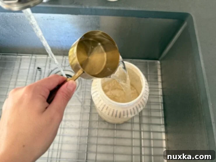 Effortless Everyday Sourdough 8 Close-up of flour, water, and sourdough starter in the container before mixing