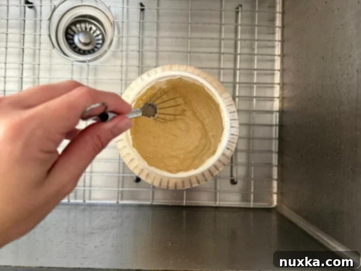 Effortless Everyday Sourdough 9 Mixing the sourdough starter, flour, and water thoroughly with a long whisk