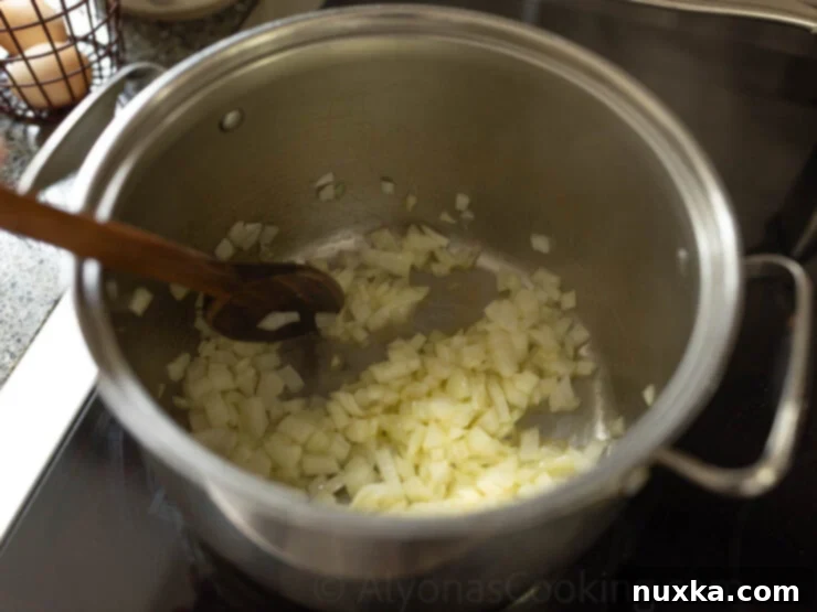 Sautéed diced onions in a pot with melted butter, ready for chicken chowder.