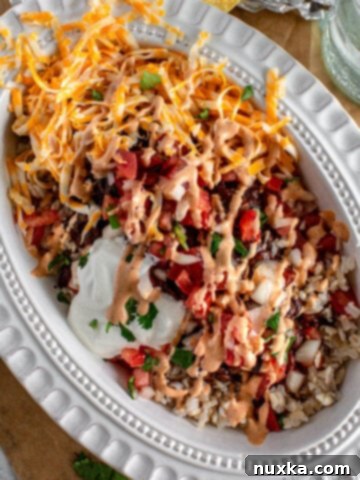 a layered burrito bowl inside an oval plate