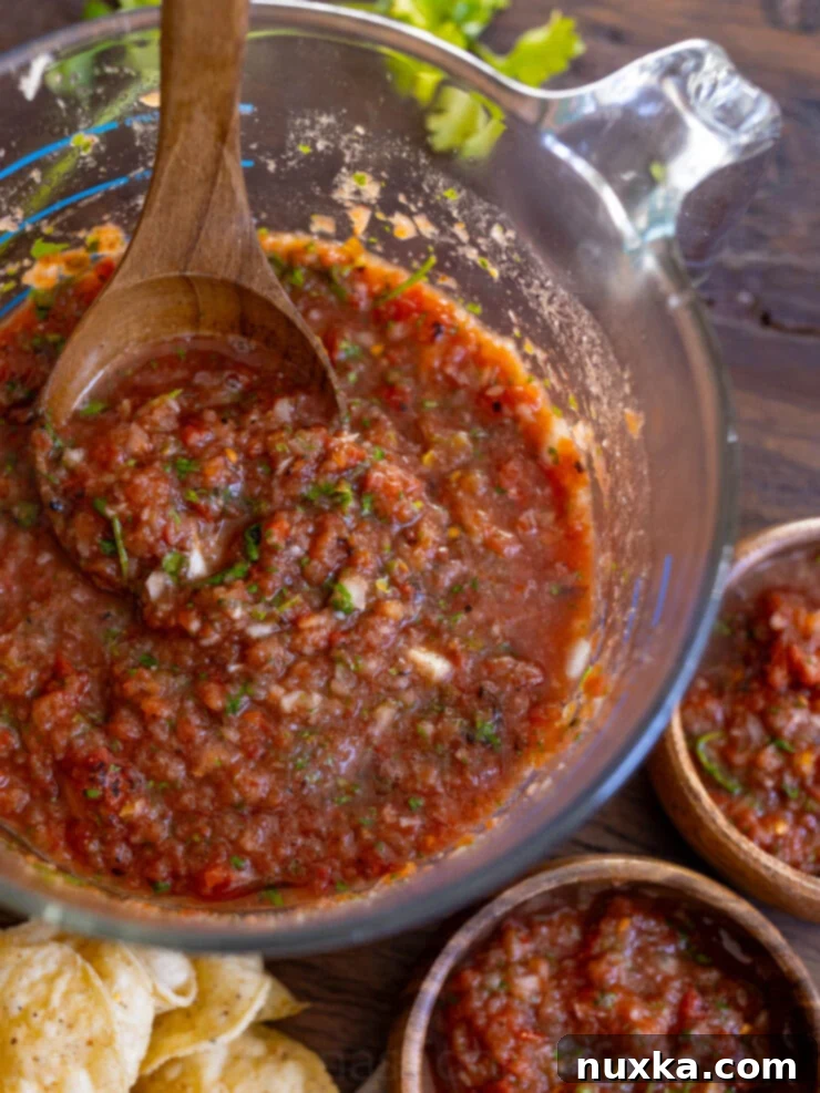image of homemade salsa blended in a large glass measuring cup with a   ladle spoon 