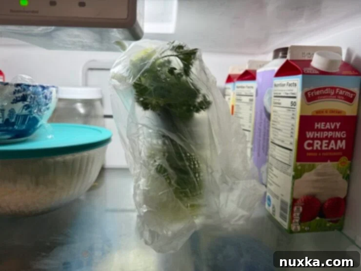 Image of fresh herbs stored in a glass of water in the fridge.