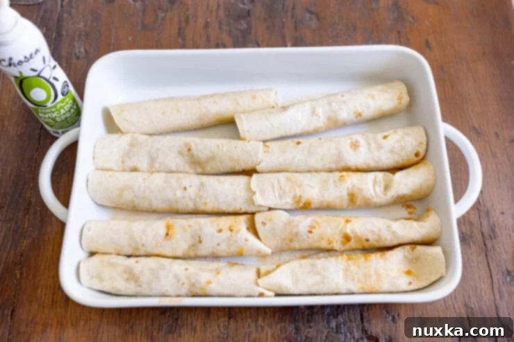 image of greased and arranged chicken enchiladas in a casserole dish