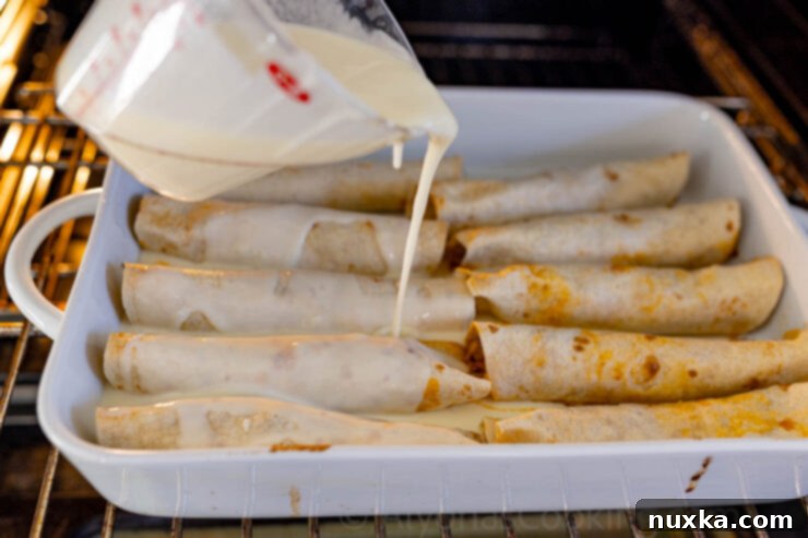 image of melted cheese sauce being poured over chicken enchiladas