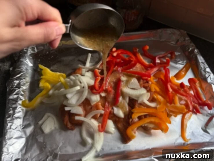 Image of Italian Dressing being poured over the seasoned chicken breasts, bell peppers, and onions